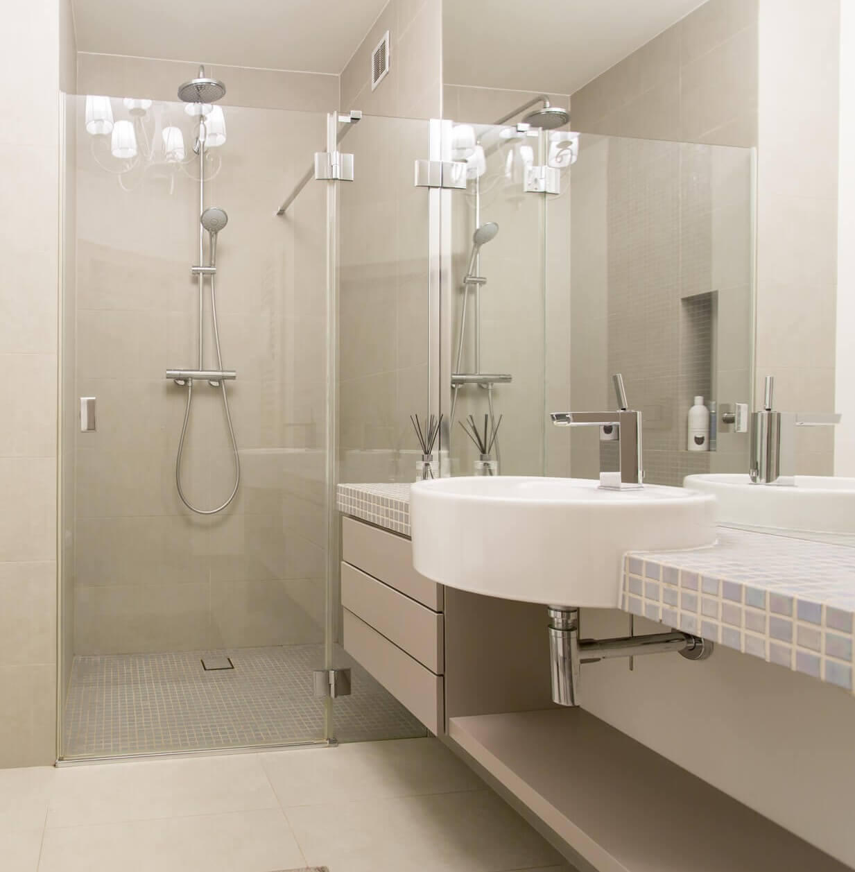 gefliestes_badezimer_mit_bodengleicher_dusche_aus_glas_und_einer_tuer