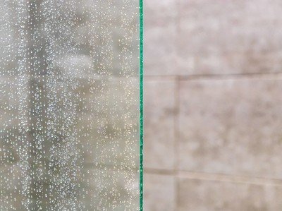 Feine Wassertropfen auf Glasscheibe im Badezimmer